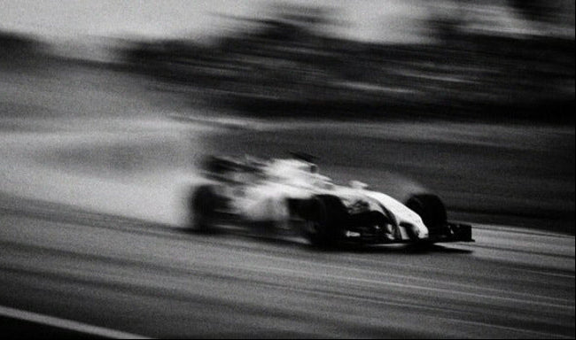 Black and white formula 1 race car on a track with motion blur